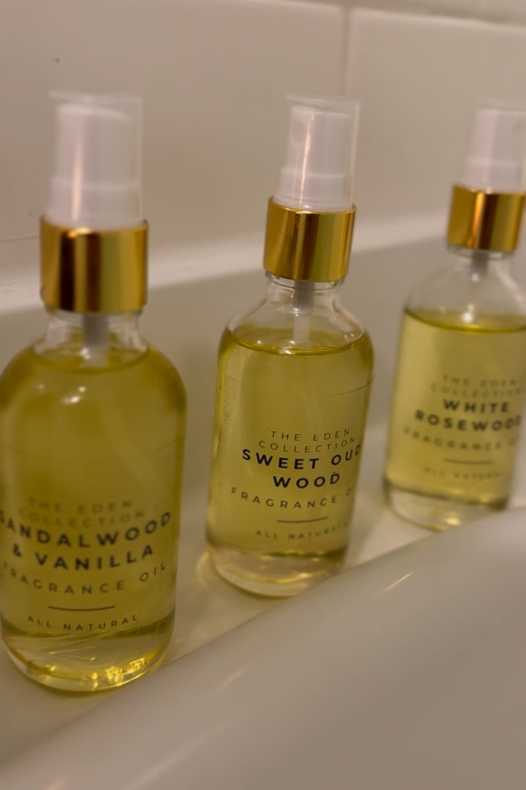 Three bottles of fragrance oils with gold caps on a white surface.