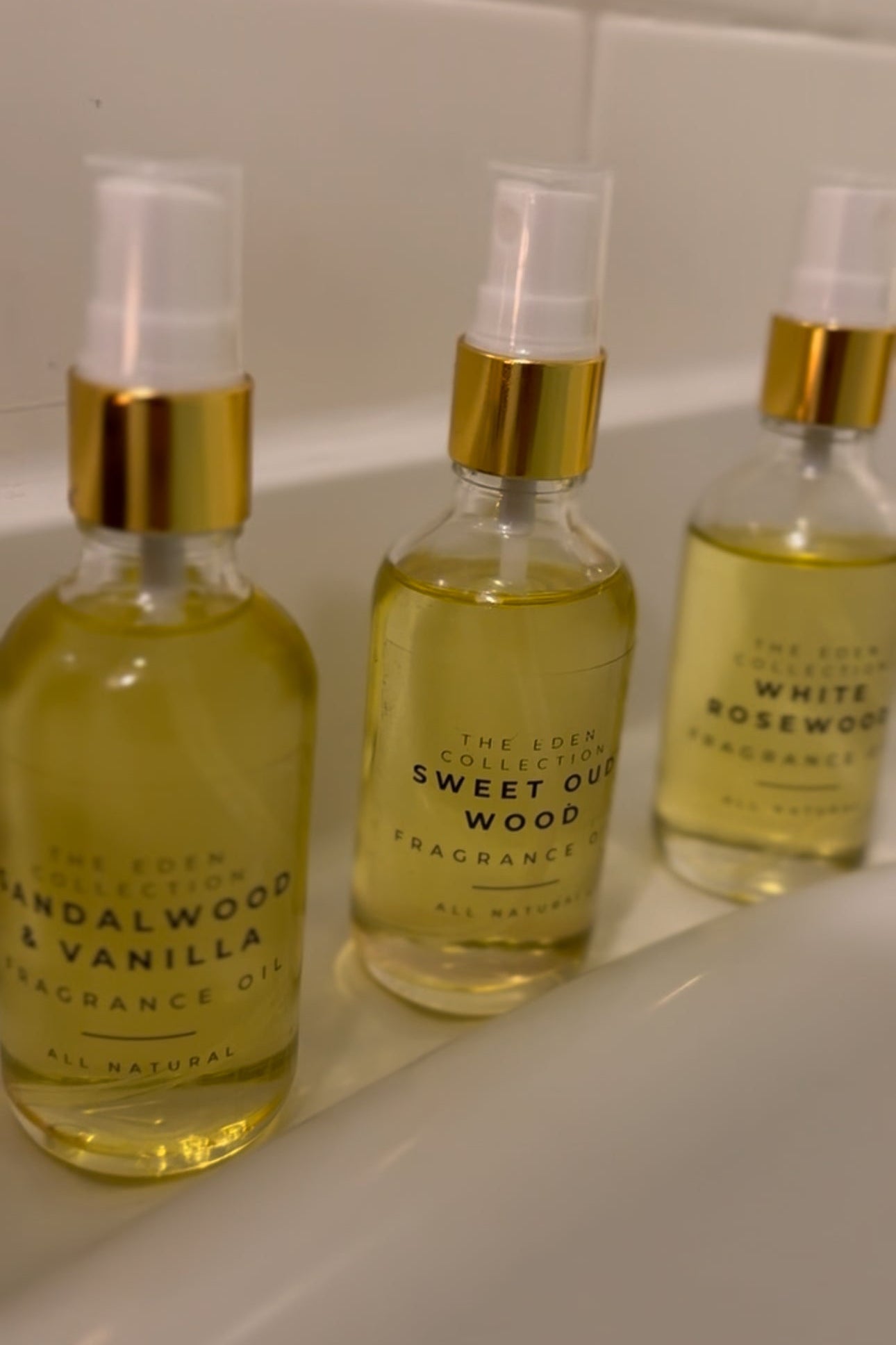 Three bottles of fragrance oils with gold caps on a white surface.