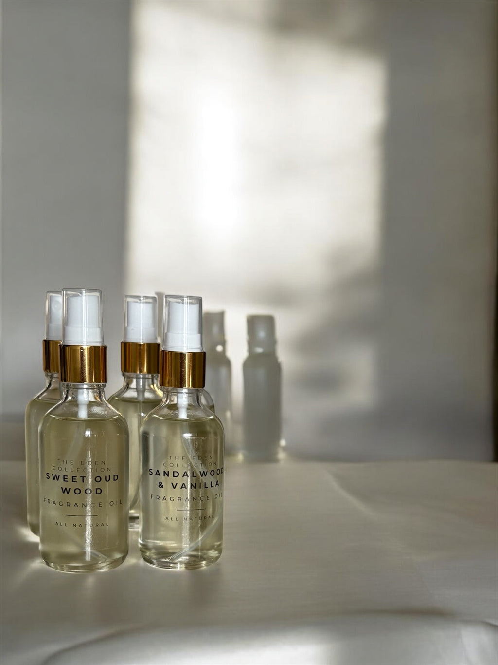 Set of perfume bottles with gold caps on a light surface with soft shadows