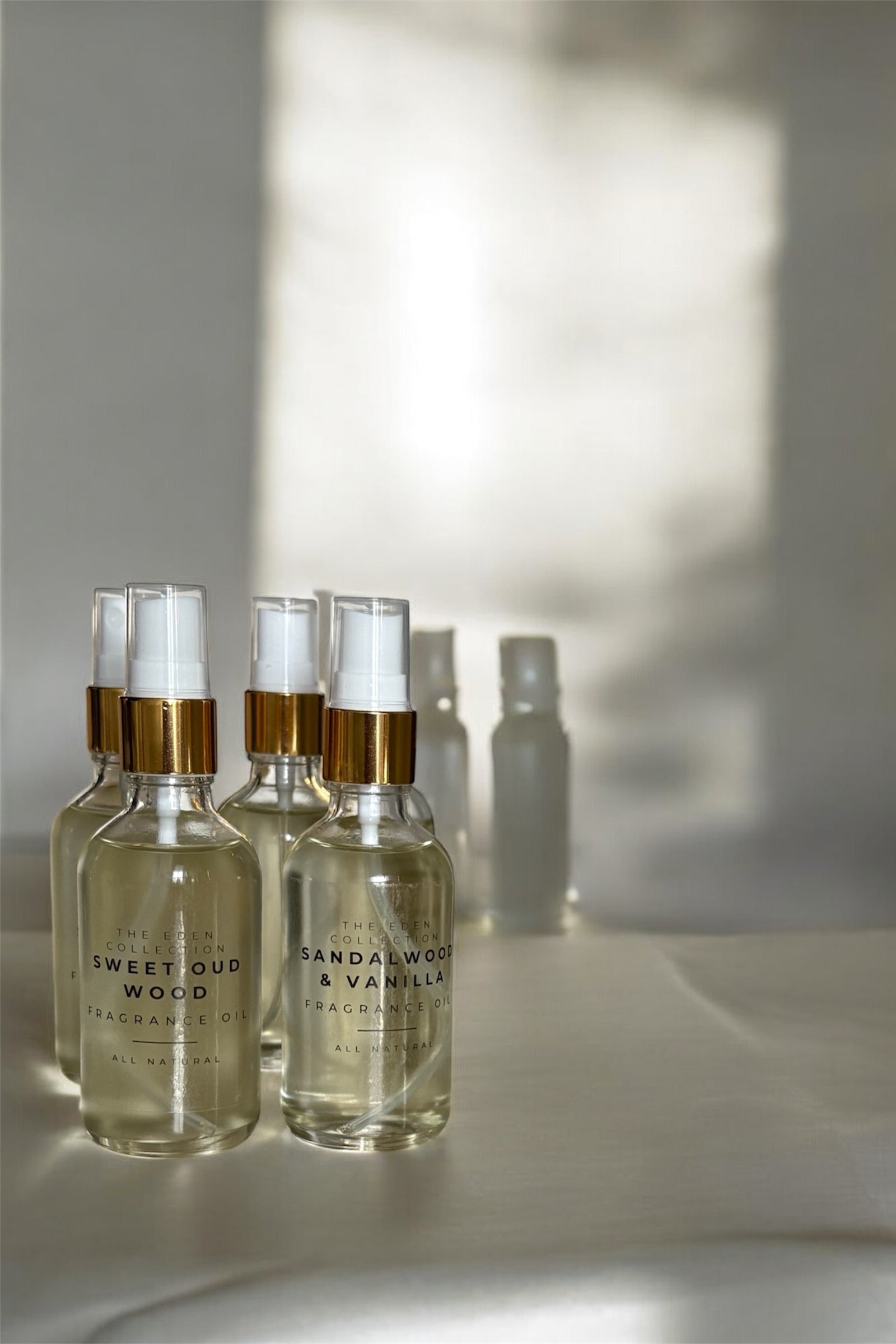 Set of perfume bottles with gold caps on a light surface with soft shadows