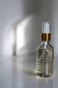 Clear glass bottle with gold cap labeled 'White Rosewood' on a reflective surface.